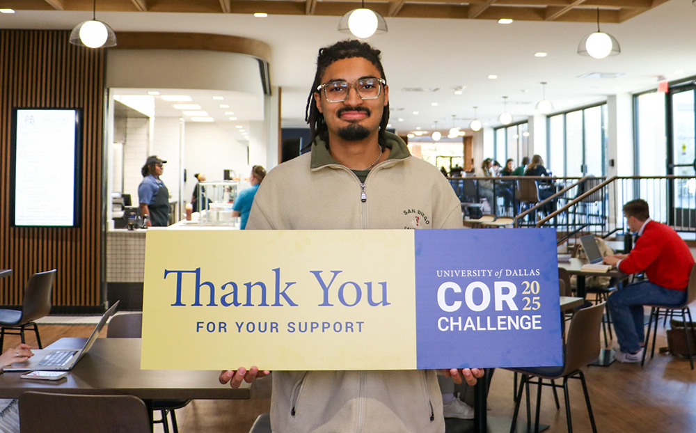 Student holding thank you sign in new dining area.